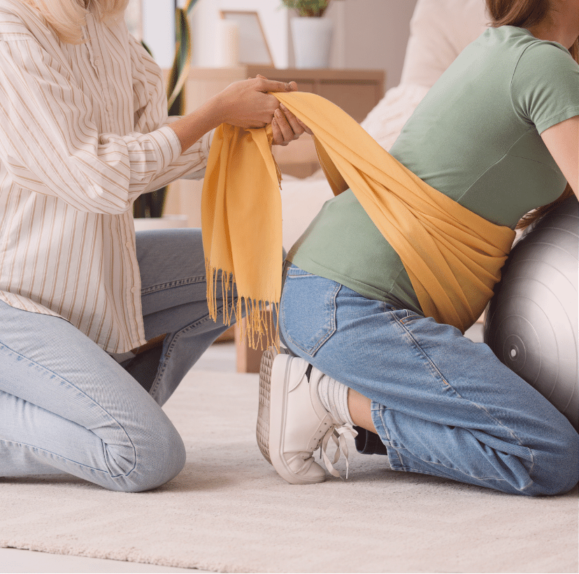 A pregnant woman and a doula during belly binding session