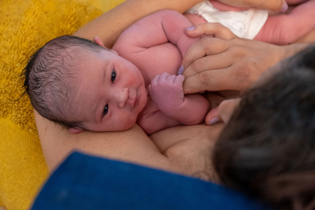 A newborn grabs her mother's hand shortly after birth at home.