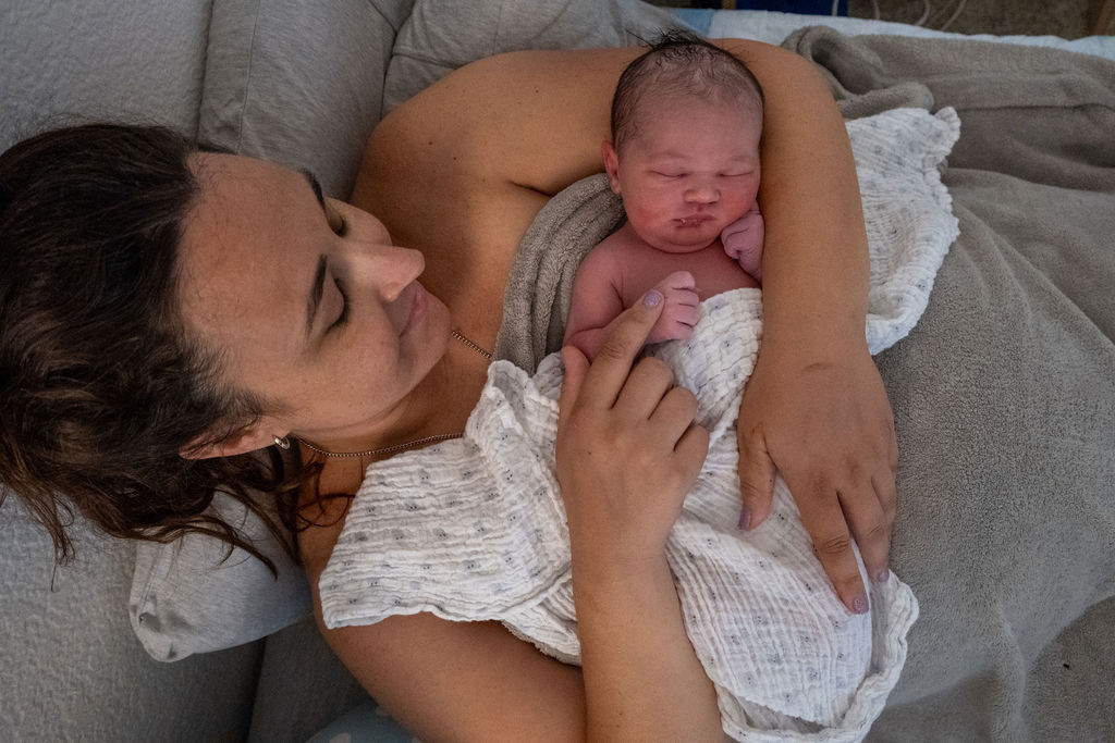 A new mother holding her newborn after giving birth naturally at home. sleep coaching orange county